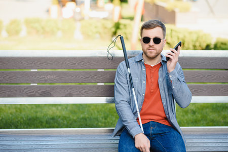 Young blinded man using phone and sending voice message.