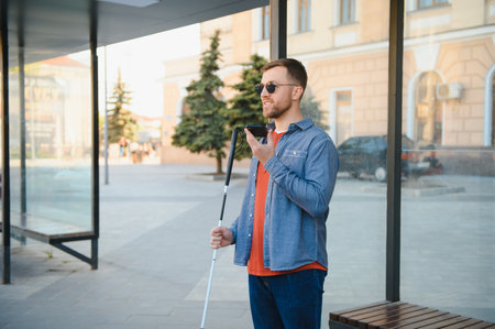 Young blinded man using phone and sending voice message.