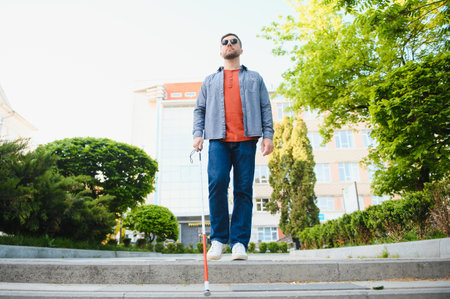 Young handsome blinded man walking with stick in town.の写真素材