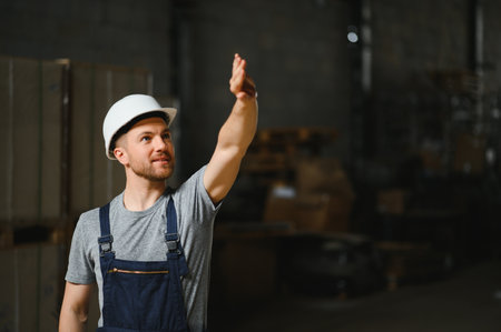 Smiling and happy employees. Industrial worker indoors in factory. Young technician with white hard hatの写真素材