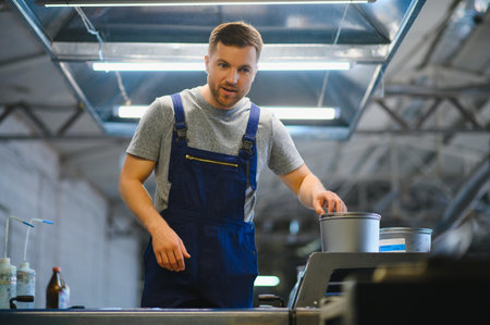 Man working in printing house with paper and paints.