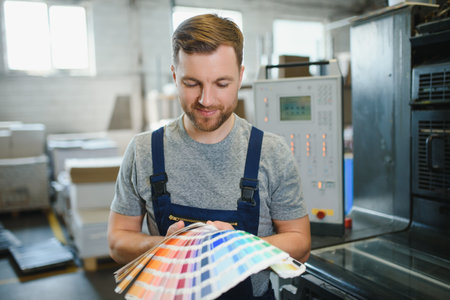 Man working in printing house with paper and paints.