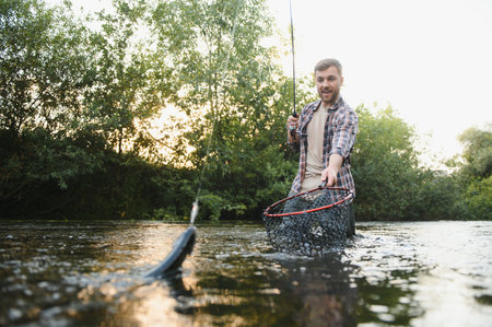Fisherman catches a trout on the river in summer.