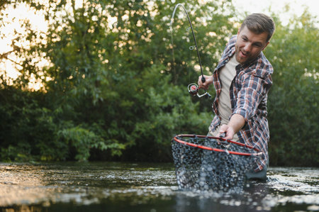 Fisherman catches a trout on the river in summer.の写真素材