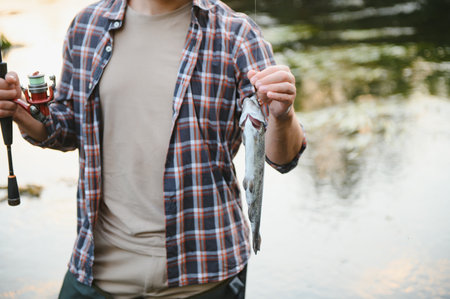 Happy fisherman holding a fish. Fishing on the beautiful riverの写真素材