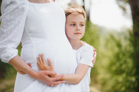 Pregnant woman and her daughter in the park at sunset. A happy familyの写真素材