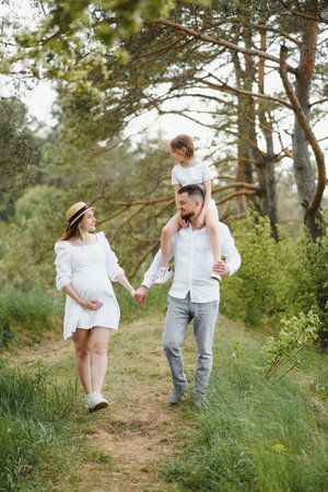 Happy pregnant couple with daughter in summer natureの写真素材