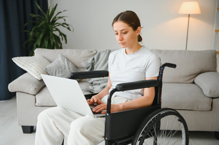 woman in a wheelchair works on the laptop PC in the home office with an assistance dog as a companion.の写真素材