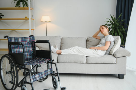 woman trying to sit down in wheelchair from couch.の写真素材