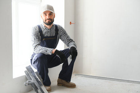 Man removes holes and bumps on the wall with a spatula and plaster.の写真素材