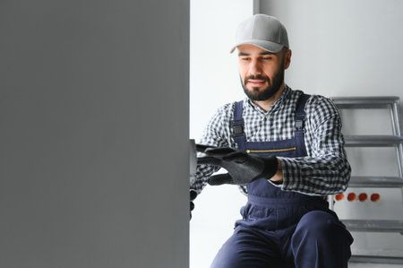 Portrait of handsome mechanic with stubble in blue overall, shirt having his arms crossed, looking at camera.の写真素材