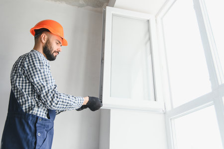Worker installing plastic window indoors.の写真素材