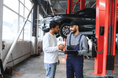 Mechanic, car servicing at garage - concept of timely customer service, car maintenance and deal agreemnetの写真素材