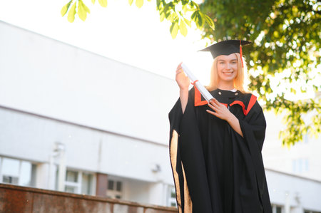 A young female graduate against the background of universityの写真素材
