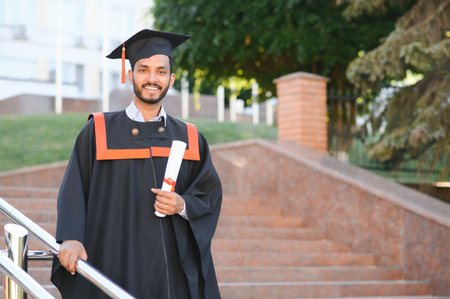 Young indian graduated boy holding his graduation degree convocation ceremony. student graduate...