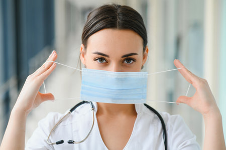 Portrait of young beautiful female medical worker,wearing uniform and protective face mask.の写真素材
