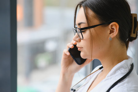 Female doctor talking by mobile phone in clinic.の写真素材