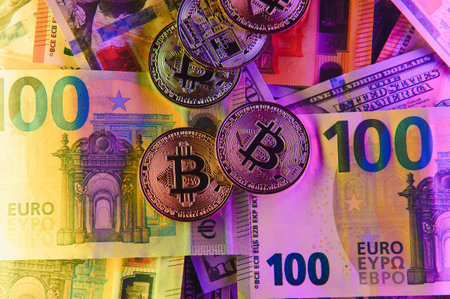golden bitcoins new virtual currency with traditional dollars and euro as a background.の写真素材