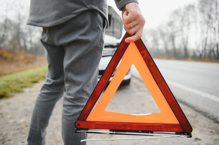 Sad driver having engine problem standing near broken car on the road. car breakdown concept.の写真素材