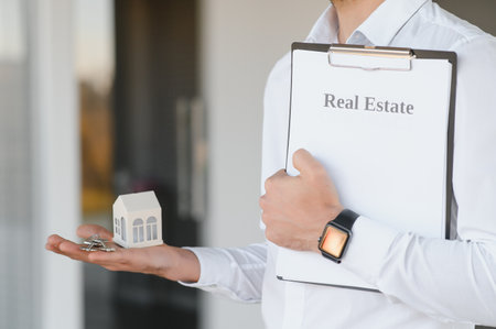 Real estate agent holding key and house model.の写真素材