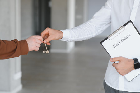 Cropped shot of Real estate agent giving a property's key to customer while standing at the orderly officeの写真素材