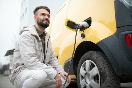 Man charging electric car by the work.