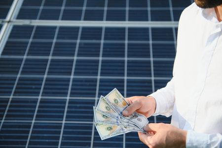 male hand hold hundred dollar at the background of solar station. concept of generation.