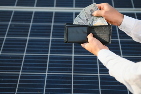 male hand hold hundred dollar at the background of solar station. concept of generation.