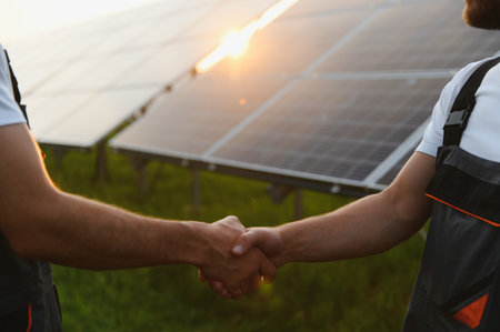 Workers shaking hands on a background of solar panels on solar power plantの写真素材