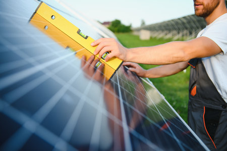 Man engineer in uniform working on solar power farm. solar panel field. Clean energy production. green energyの写真素材