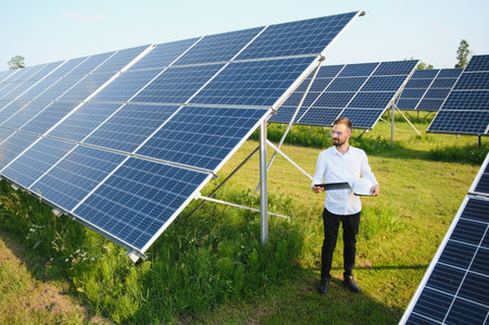Male worker solar power plant on a background of photovoltaic panels