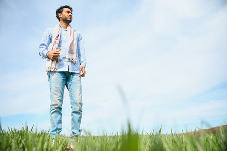 worry less ,indian farmer standing in his healthy wheat field.の写真素材