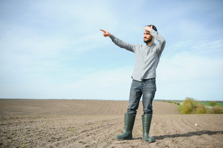 A young farmer inspects the quality of wheat sprouts in the field. The concept of agricultureの写真素材