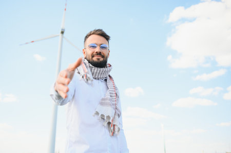 Arab man standing with wind turbine on mountain.の写真素材