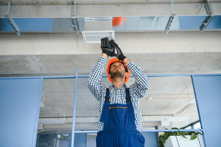 hvac indian worker install ducted pipe system for ventilation and air conditioning. copyspace.の写真素材
