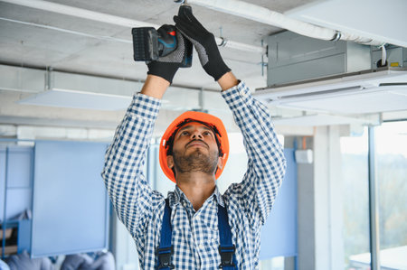 hvac indian worker install ducted pipe system for ventilation and air conditioning. copyspace.の写真素材