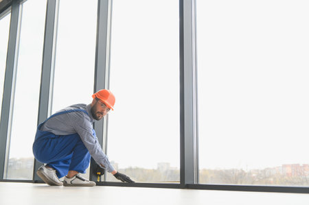 The foreman installs a window frame in the room.の写真素材