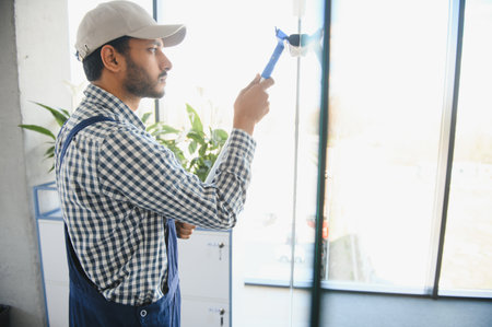 Young indian man washing window in office