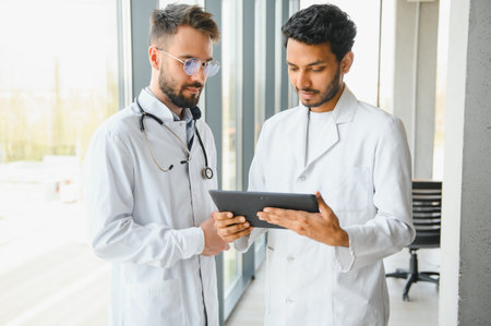 An Indian doctor and a European doctor stand together in a hospital lobby.の写真素材