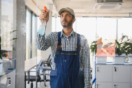Male janitor cleaning window in office.の写真素材