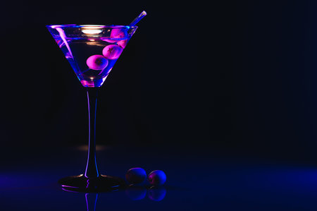 Martini glass and olives on a black background with neon lights.の写真素材