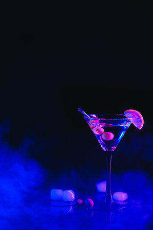 Martini glass and olives on a black background with neon lights.の写真素材