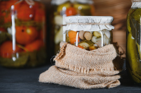 Jars of pickled vegetables on rustic wooden background.の写真素材