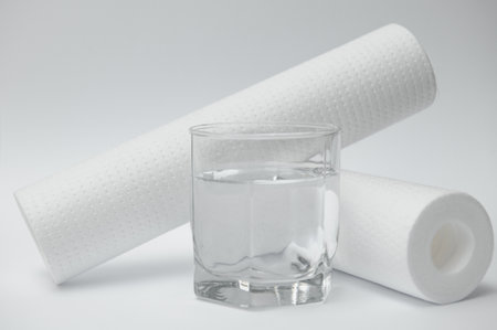 water filters. Carbon cartridges and a glass on a yellow background. Household filtration system.の写真素材