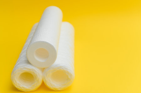 water filters. Carbon cartridges and a glass on a yellow background. Household filtration system.の写真素材