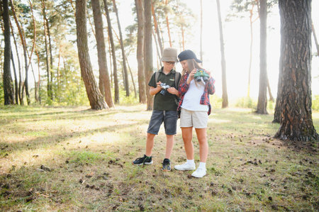 Happy excited school children with backpacks in casual clothes enjoying walk in forest on sunny...