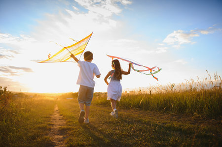 Children launch a kite in the field at sunset.の写真素材