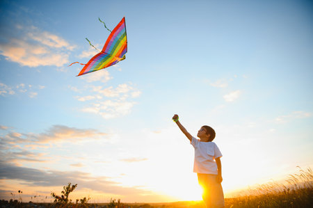 Boy is running with a kite during the day in the field.の写真素材