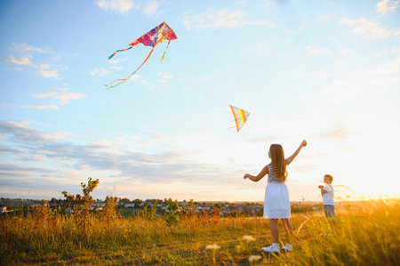 Happy children launch a kite in the field at sunset. Little boy and girl on summer vacationの写真素材