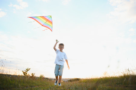 Boy is running with a kite during the day in the field.の写真素材